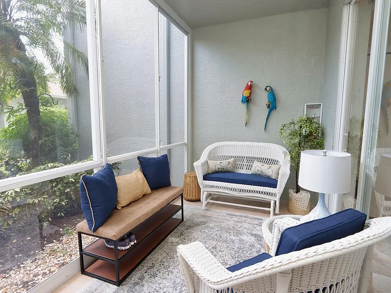 Front enclosed veranda with beautiful views of the palm trees and plants in the community ... Perfect place to enjoy your morning coffee or a great book