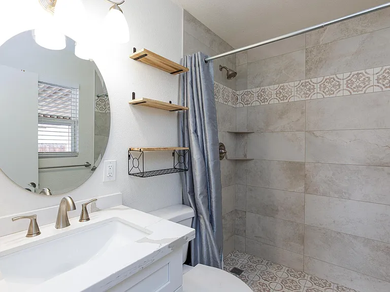 Tile shower with shelves and extra shelves on the wall.