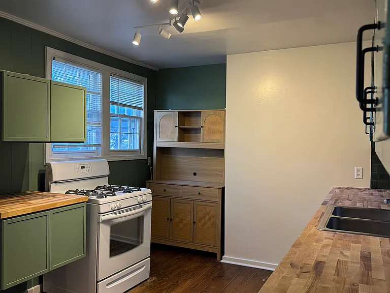 Kitchen with pantry and butcher block prep station and cabinets next to stove. Refrigerator (not shown) is to the left of the cabinets.