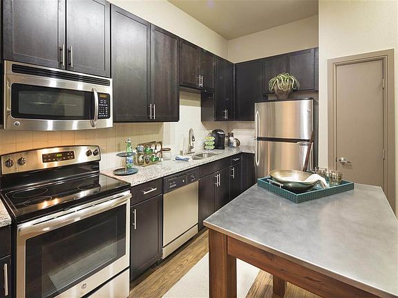 Kitchen with granite counter-tops, sleek espresso-colored cabinetry, and stainless steel appliances