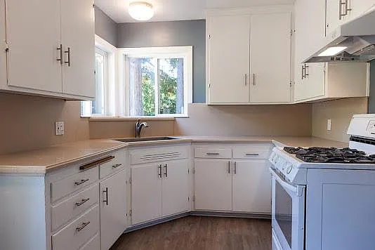 Half of small kitchen. Out of view on the left side is a nook area with windows, on the right is the doorway to living room and the refrigerator