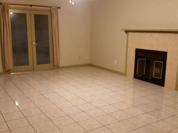 Spacious living room with ceiling fan. French doors lead to