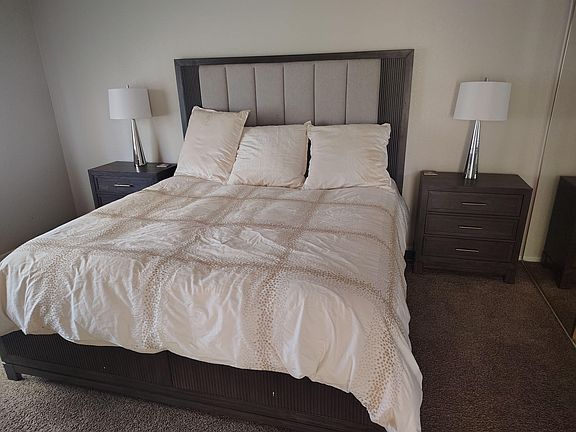 Spacious bedroom featuring a large bed with upholstered headboard, matching nightstands, and bedside lighting.