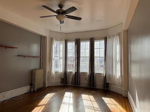 Living Room with 10 ft. ceilings, hardwood floors, shelving and ceiling fan. Let the sun shine!