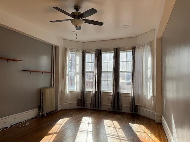 Living Room with 10 ft. ceilings, hardwood floors, shelving and ceiling fan. Let the sun shine!