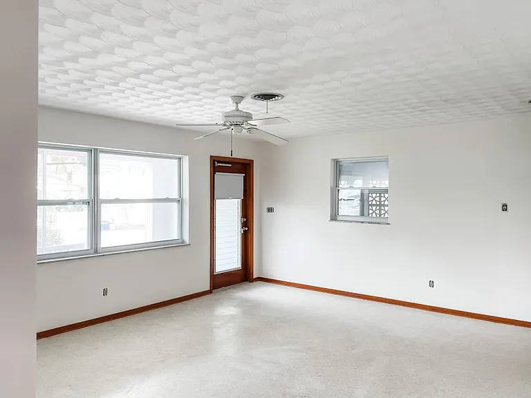 The main entrance into the spacious living room. (Blinds on front window will be added.) Living room is 18 x 15, with dining area behind it. House has much desired terrazzo floors throughout!