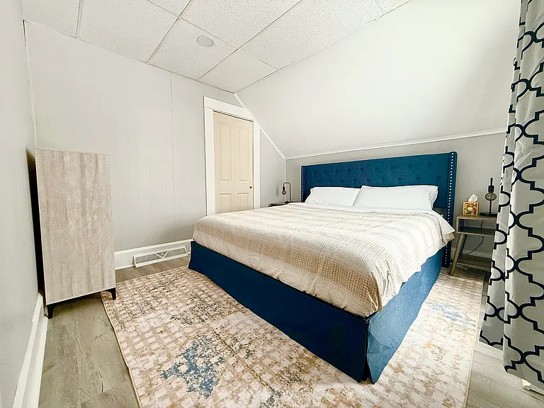 The secondary bedroom features a king-size bed, plenty of natural light, black-out shades for privacy, and a closet with a dresser for convenient storage.