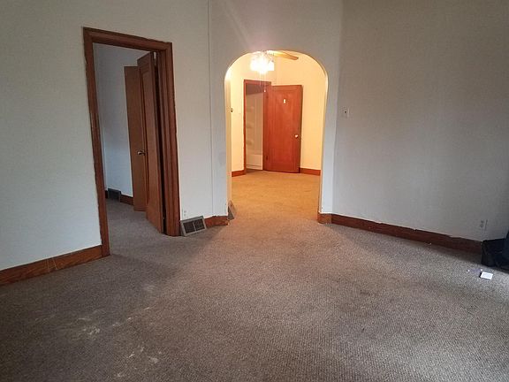 View from the living room. Smaller bedroom is on left. Archway leads to dining room with bathroom door in far middle.