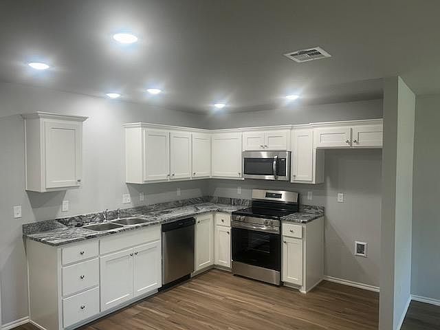 Kitchen with stainless dishwasher, microwave and electric stove. Laundry room with washer/dryer hookup is connected.