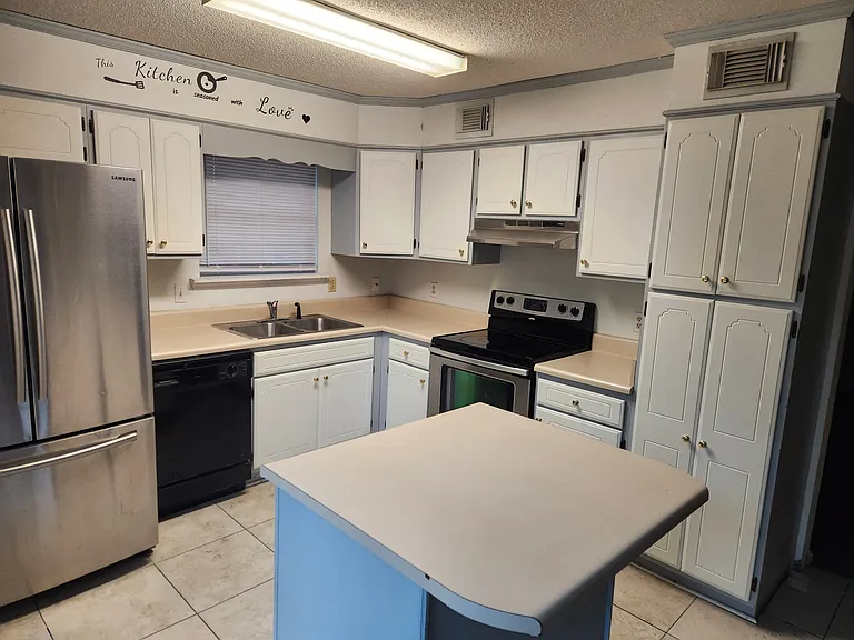 Tile floor, stainless appliances, glass top stove/oven, island with drawers and cabinet space