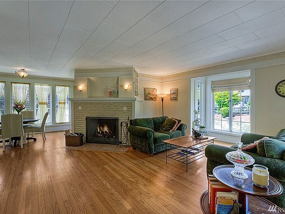 Large open concept living room and dining room with a traditional wood burning fireplace. Large windows flood the room with lots
