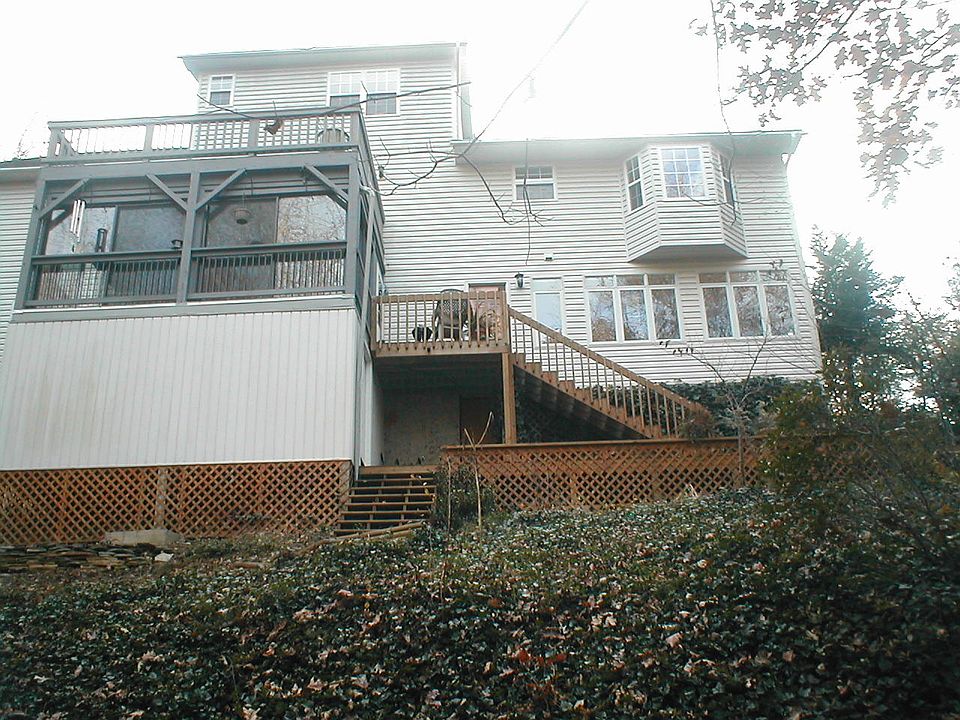 Back of the house . It shows the lower level apatmentwith the 6 windows as well as a small deck off one of the apartment doors and also the patio door enclosed florida room