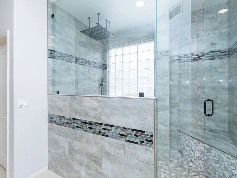 Spacious primary suite offers upgraded oversized walk-in shower, dual benches, & a 24'' rainforest-style shower head
