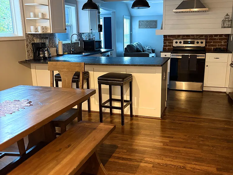 Open kitchen with breakfast bar seating, stainless range and hood, ample counters, and sightlines into the living area.