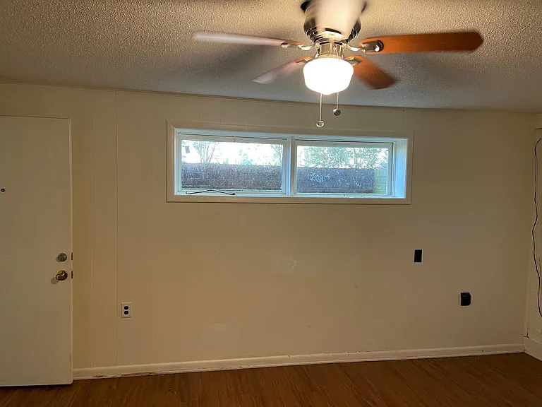 Looking at one wall of den and living room with windows for natural light and ceiling fan