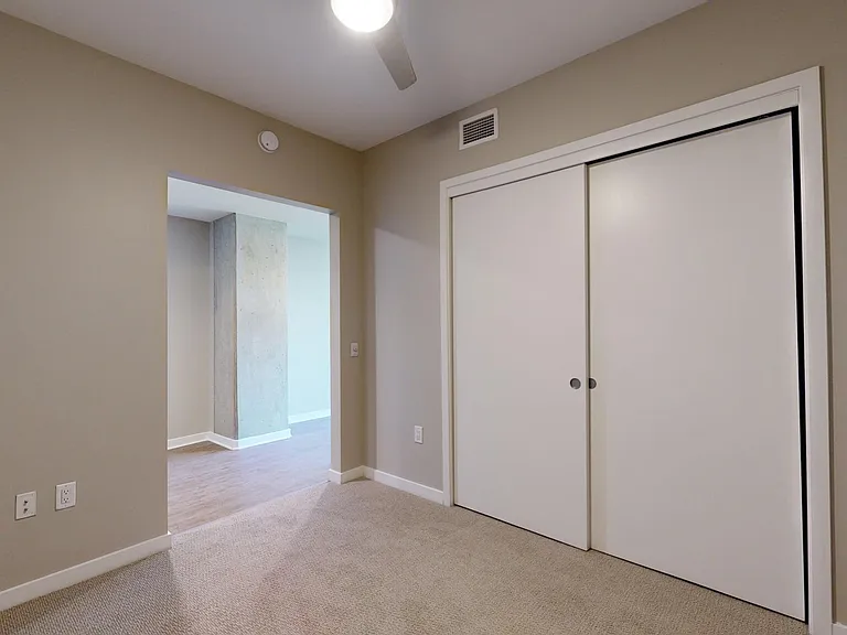 Spacious apartment bedroom with plush carpet flooring.