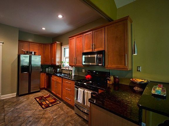 Beautiful open kitchen features warm stained cabinets, stone counters, stainless appliances and breakfast bar that opens to huge family room