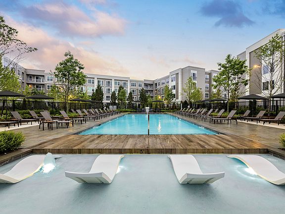 Relaxing resort-style pool featuring ample lounge seating with umbrellas for shaded seating