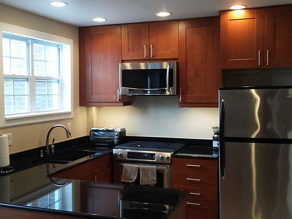 Renovated kitchen with new cabinetry, granite countertops, and oversized stainless steel refrigerator, gas range, dishwasher, and garbage disposal