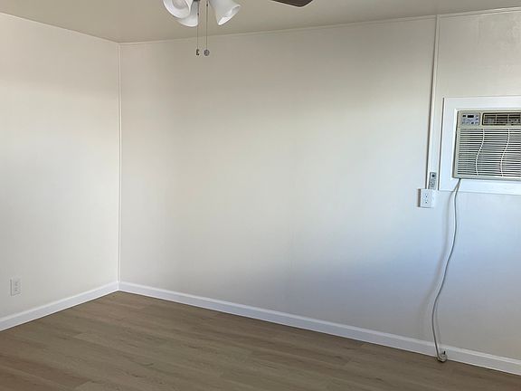 Living Room with New Ceiling Fan, wall A/C unit, brand new wood flooring, freshly painted, new windows with blinds.