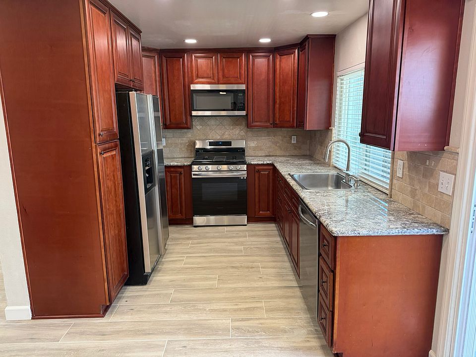 Kitchen with trvertine back splash and window behind sink with view of patio yard.