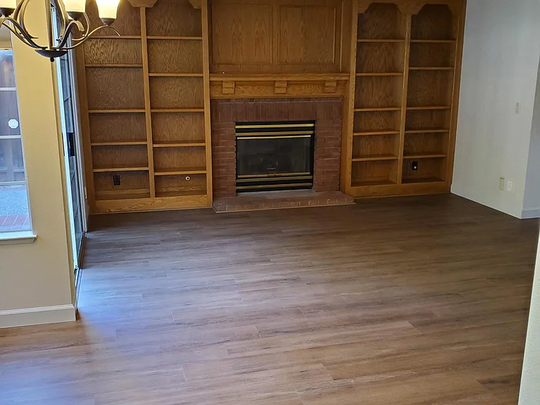 View of comfortable family room with built-in bookcase, and fireplace from kitchen