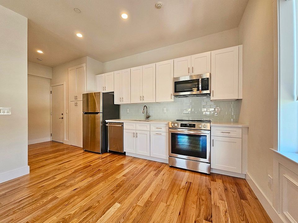 Sleek & modern inviting kitchen with hardwood floors, stainless steel appliances, and crisp white cabinets. The tile backsplash and recessed lighting create a clean, modern feel_perfect for cooking and gathering.