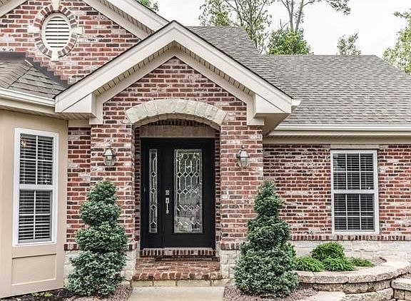 Stately entry with brick pavers on porch, leaded glass door and side lite, and professional landscaping.