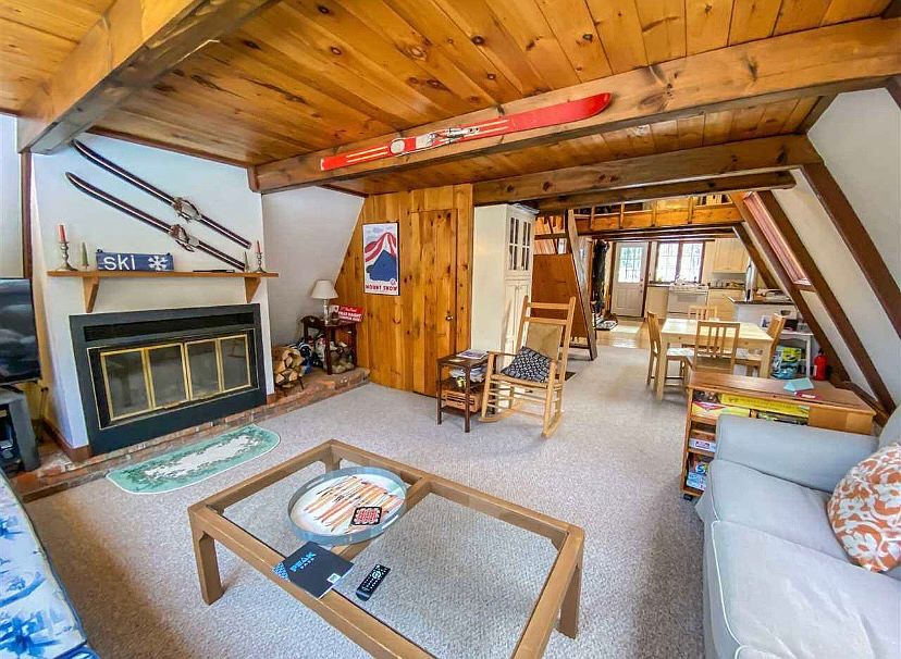 Living room with TV and wood fireplace.