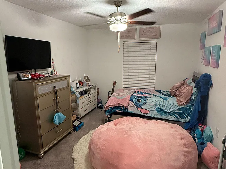 Private bedroom with a ceiling fan, window with blinds, and space for a bed plus dresser, TV, and nightstand storage.
