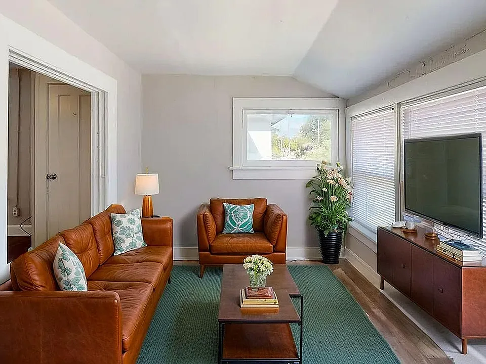 Inviting living room featuring a stylish brown leather sofa set, modern decor, and abundant natural light from large windows.
