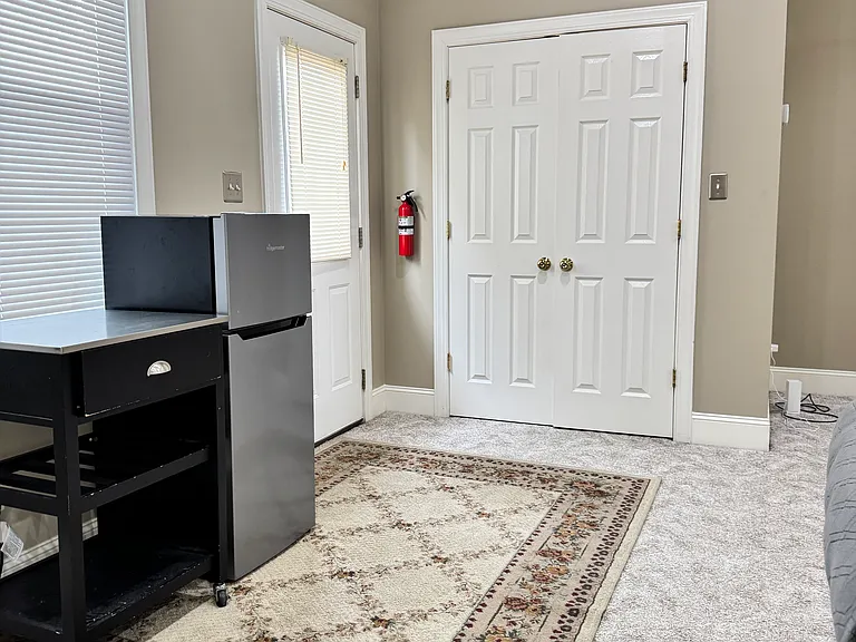 This 600 sq ft private suite boasts brand-new, soft wall-to-wall carpet throughout, a bright vaulted-ceiling bedroom with a Queen-size bed, cozy sofa, coffee table and ceiling fans, plus abundant natural light from multiple windows.