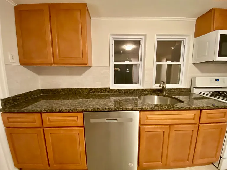 dish washer, kitchen cabinets, granite counter top and microwave all surrounded with backsplash.