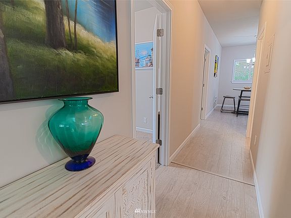 Hallway leading to the kitchen with bedrooms to the left and bathroom on the right.