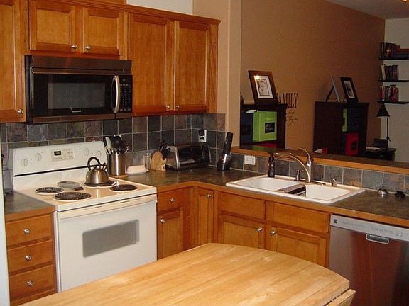 Large kitchen with slate surround tile, double sink & stainless dishwasher. Stove is plumbed for gas. Opens to living & dining areas. Slider in kitchen leads out to BBQ patio.