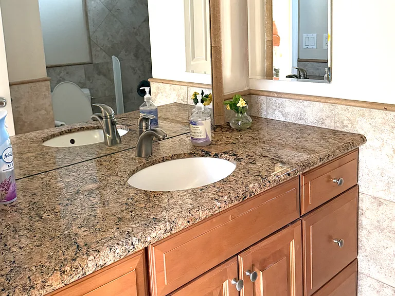 Hall bathroom with granite countertops & new cabinets. Large mirror and vanity mirror. Plus tile floors!
