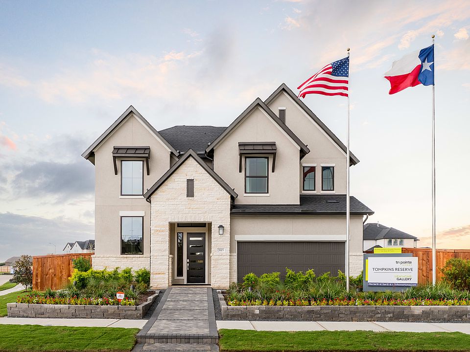 A two-story residential house with a garage, surrounded by a well-manicured lawn and landscaping, wi