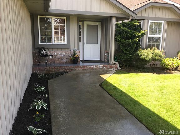 Side view showing open space, private patio, living room windows and east garage wall.