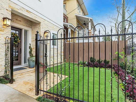 Front yard is enclosed with a wrought-iron fence & gate and was recently landscaped with artificial turf.