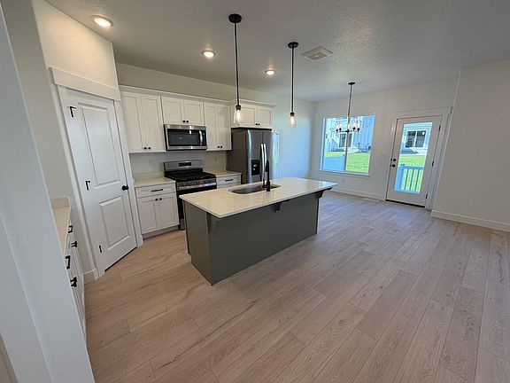 This home features a bright, modern kitchen with white shaker cabinets, stainless steel appliances, and a large center island with a sleek undermount sink.