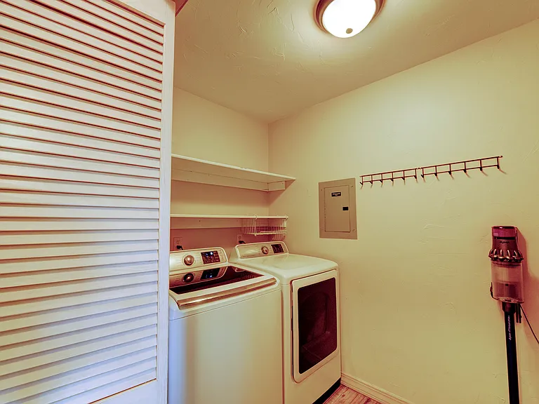Laundry room with washer and dryer, rolling storage and shelves for cleaning supplies.