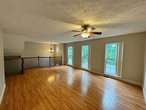 Spacious and bright living room with ceiling fan and vaulted entry