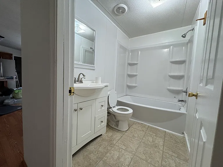 Second Bathroom
Features a new tub/shower combination with built-in shelving, a modern vanity, updated lighting, and durable tile-look flooring. Freshly painted and move-in ready.