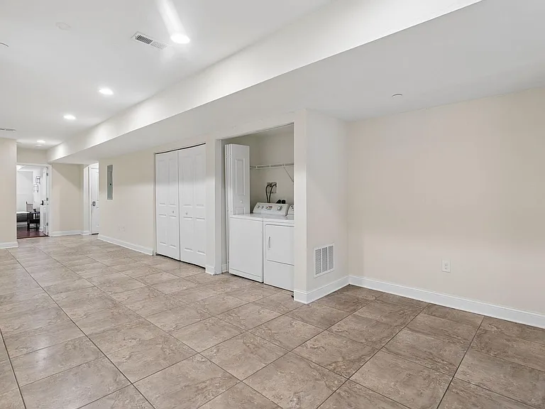 Spacious tiled lower-level area with recessed lighting, double closet storage, and an in-unit washer/dryer nook.