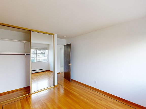 Bright bedroom with wood-like floor and a closet with mirror