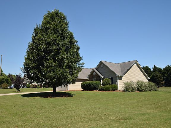 Fenced back yard; butterfly bushes line the side of the home