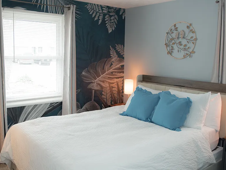 A peaceful retreat featuring a stunning botanical accent wall and a cozy queen-sized bed.