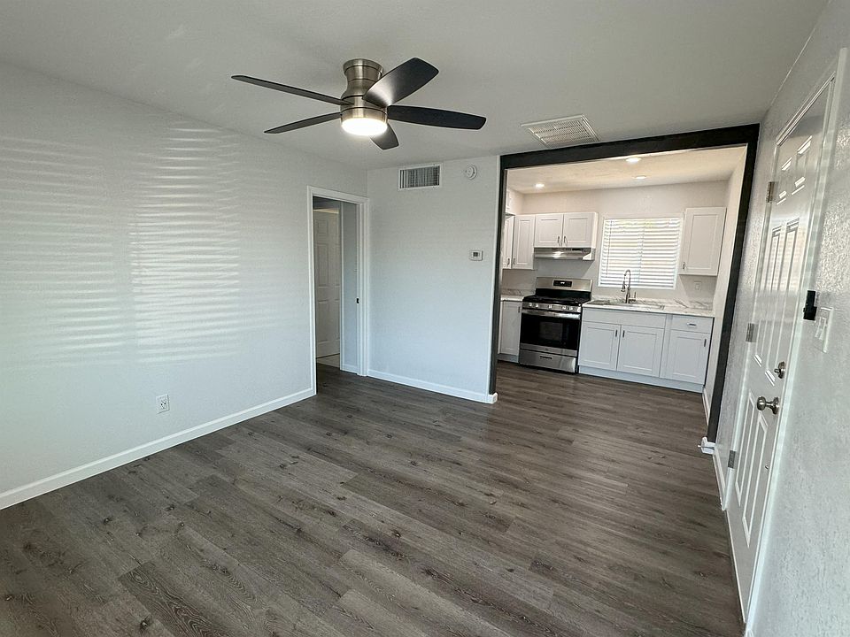 Large living room with open kitchen and vinyl flooring.
