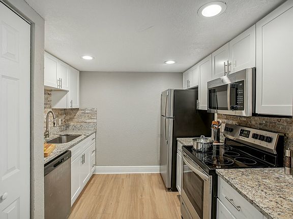 Modern kitchen with sleek stainless steel appliances, elegant granite countertops, and white cabinetry for a contemporary style.