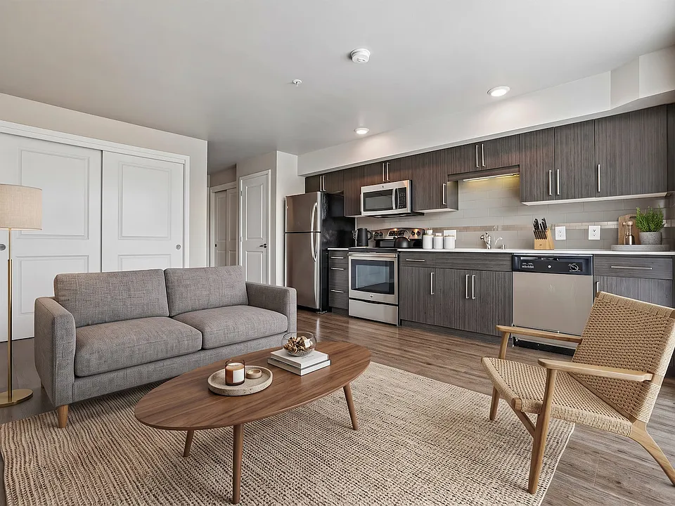 Open-concept layout featuring a modern kitchen with stainless steel appliances and an adjoining living area at Ludwig Apartments.
